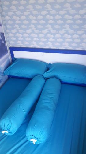 uma cama azul com almofadas azuis em Apartemen Springlake Summarecon Lobby Basella 1023 Two Bedroom em Rawabugel