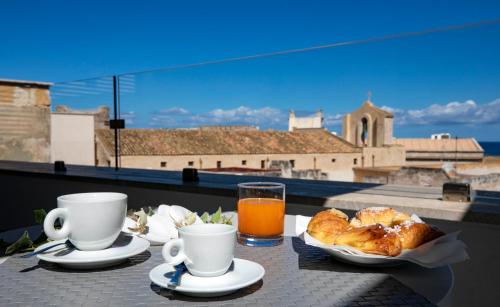 una mesa con café y cruasanes y un vaso de zumo de naranja. en Azzoli Trapani - Apartments&Skypool - Adults Only, en Trapani