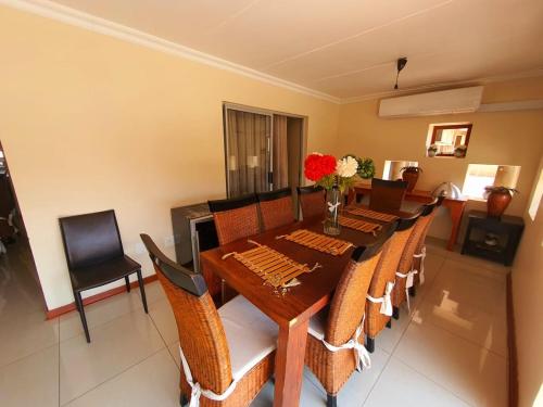 a dining room with a wooden table and chairs at Tenacity Guesthouse - Riviera Park in Mahikeng
