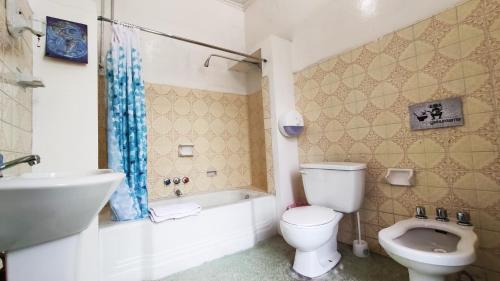 a bathroom with a toilet and a tub and a sink at Hostal Yakumama in Cuenca