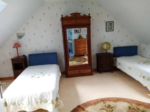 a bedroom with two beds and a mirror at Gîte à la ferme in Merléac