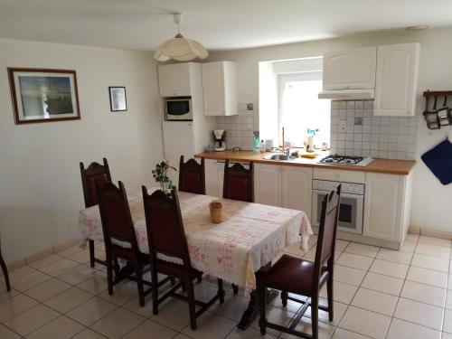 Merléac的住宿－Gîte à la ferme，一间带桌椅的厨房和一间带白色橱柜的厨房