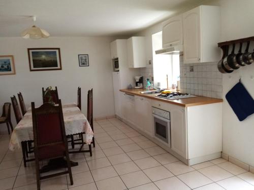 een keuken en eetkamer met een tafel en een tafel en stoelen bij Gîte à la ferme in Merléac