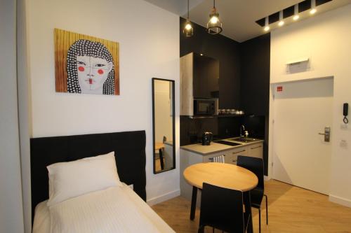 a bedroom with a bed and a table and a kitchen at Apartamenty Nowa Kamienica Częstochowa Centrum Szymanowskiego 22A in Częstochowa
