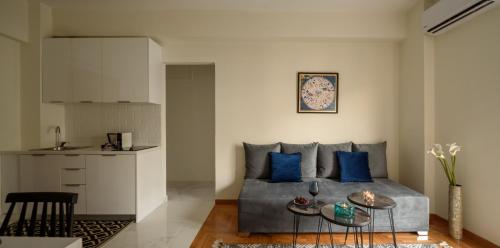 ein Wohnzimmer mit einem Sofa und blauen Kissen in der Unterkunft Acropolis Grand Apartment in Athen