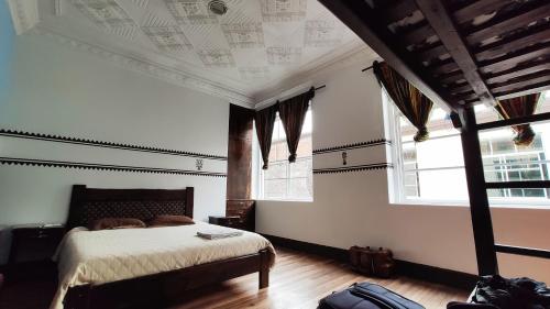 a bedroom with a bed and two windows at Hostal Yakumama in Cuenca