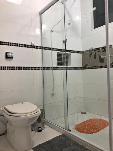 a bathroom with a toilet and a glass shower at Casa azul Ilha Grande in Abraão