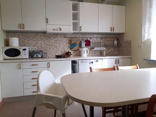 eine Küche mit weißen Schränken sowie einem Tisch und Stühlen in der Unterkunft Svētgravas in Aklaisciems