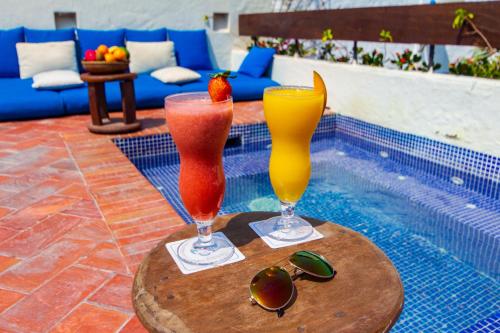 two cocktails on a table next to a swimming pool at Hotel Quadrifolio in Cartagena de Indias