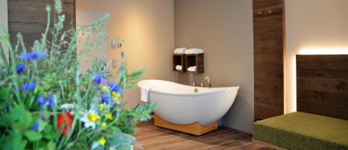 ein Bad mit einer Badewanne und Blumen in einem Zimmer in der Unterkunft Hotel Bergwirt in Herrieden