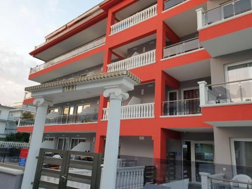 a red building with white balconies and columns at M & M White Luxury in Paralia Katerinis