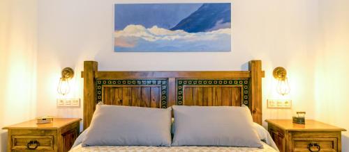 a bedroom with a large wooden bed with two night stands at Apartamentos Entre Senderos in Capileira