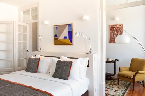 a bedroom with a white bed and a chair at Casa Balthazar in Lisbon