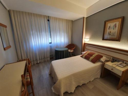 ボイロにあるHotel Alda Boiroのベッドとテーブルが備わるホテルルームです。