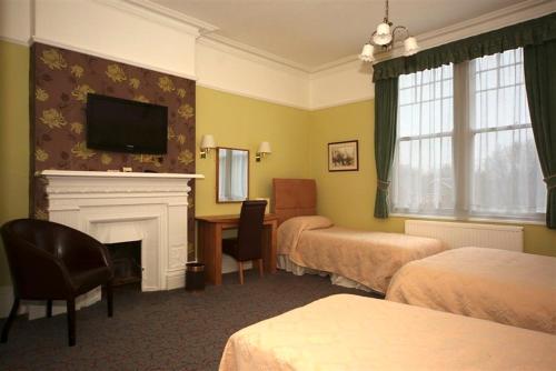 a hotel room with two beds and a fireplace at Eskdale Lodge in Sale