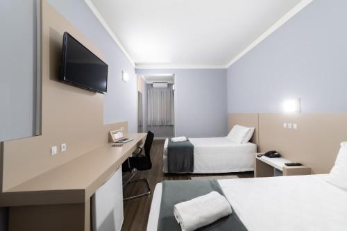 フロリアノポリスにあるRede Andrade Cecomturのベッド1台とテレビが備わる小さなホテルルームです。