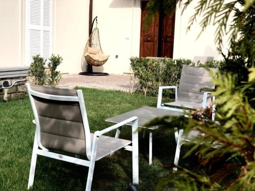 two white chairs and a table in the grass at Relais Villa Montedonzelli in Naples