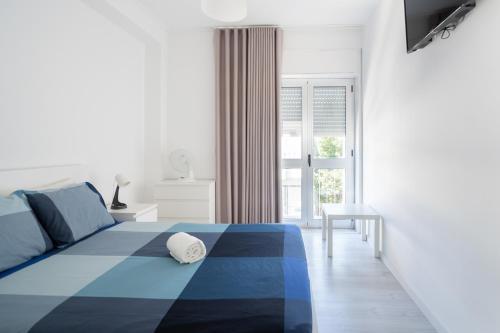 a bedroom with a blue and white bed and a window at Moreira 284 in Porto
