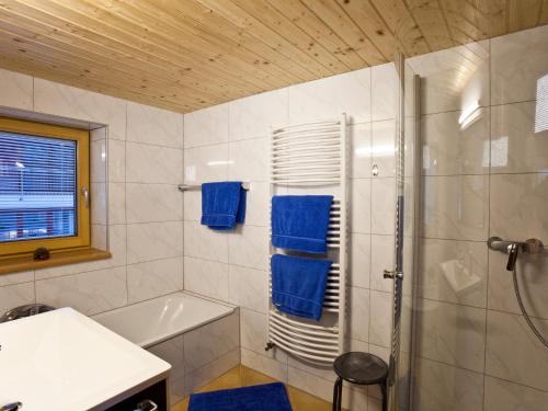 baño con bañera y ducha con toallas azules en Haus Ricarda, en Lech am Arlberg