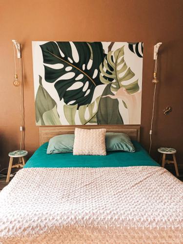 a bedroom with a bed with a painting on the wall at chambre salle de bain partagée in Cognac