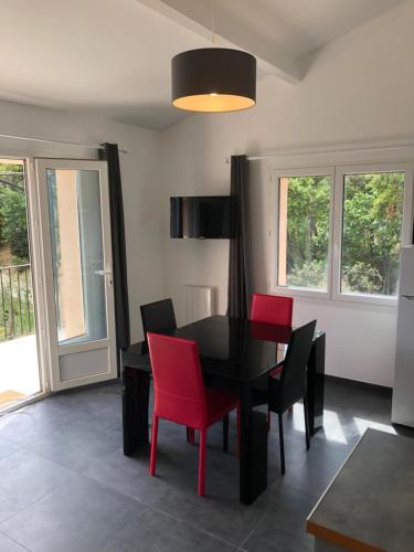 a dining room with a black table and red chairs at L'Oliveraie in La Londe-les-Maures