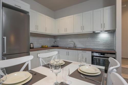 a kitchen with white cabinets and a table with wine glasses at Spilia Village Hotel & Villas in Spiliá