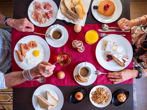 een groep mensen die aan een tafel zitten met ontbijtproducten bij B&B Alma in Lucca