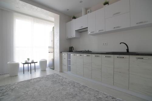 a kitchen with white cabinets and a table and a window at Ніжність in Rivne