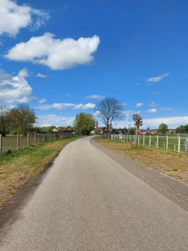 an empty road with a fence and a blue sky at Ferienwohnung Urlaub mit Pferd, Hof Müggenburg in Stüdenitz