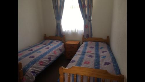two beds in a small room with a window at 313 Sundowner Holiday Park Hemsby in Hemsby