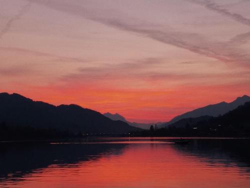 a sunset over a body of water with mountains at Haus Birke in Weissensee