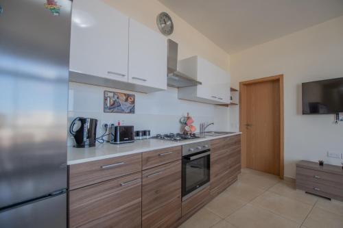 a kitchen with wooden cabinets and stainless steel appliances at KERNICE Penthouse with Sea and Country Views of Xghajra in Xgħajra