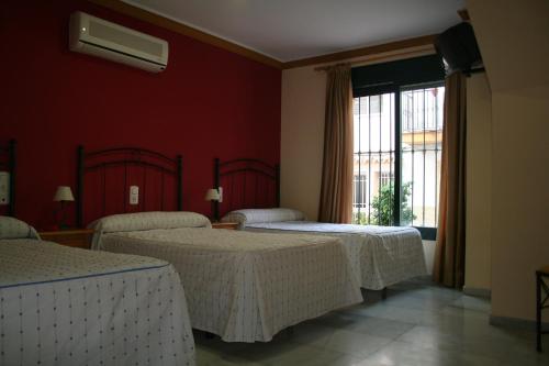 Habitación de hotel con 3 camas y ventana en HOSTAL EL MOLINO, en Marbella