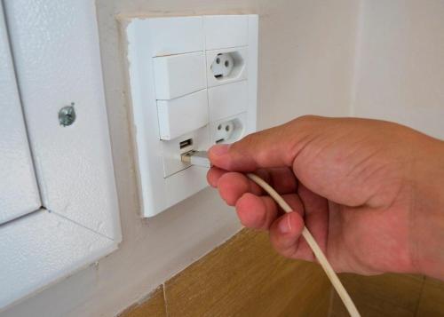 a person holding a wooden stick in front of an electrical outlet at Hotel Ipiranga Maringa in Maringá