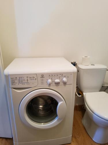 une salle de bain avec machine à laver et toilettes dans l'établissement Appartement le Tilleul - Apparts Cosy, à Saint-Pons