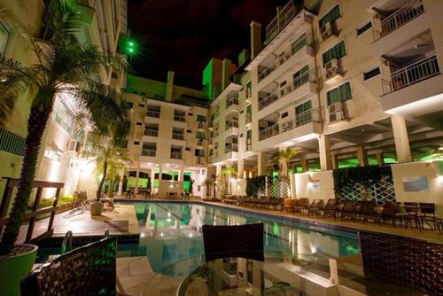 a large hotel with a swimming pool at night at Apartamento Bombinhas Summer Beach in Bombinhas