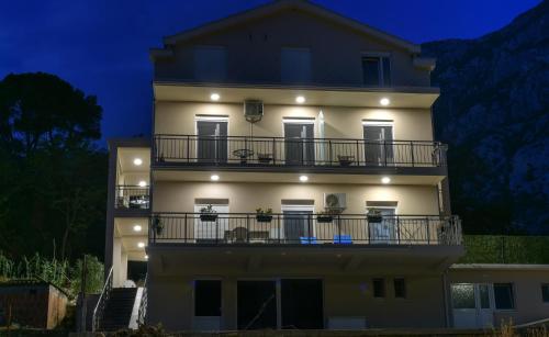 a large white building with a balcony at night at Java Apartments in Dobrota