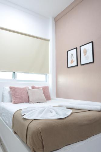 a white bedroom with a large bed with pink pillows at Hotel Boutique Kinyaah in Mérida