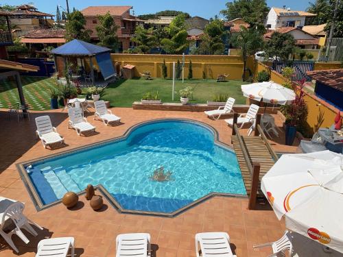 - une piscine avec des chaises et des parasols sur une terrasse dans l'établissement Pousada dos Corais, à Itaúnas