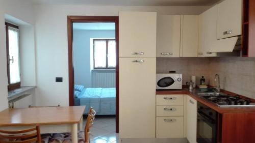 cocina con armarios blancos, mesa y comedor en Appartamento Le Cascate, en Cittiglio