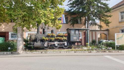 a train is sitting in front of a building at Prenoćište " Ruža" in Višegrad