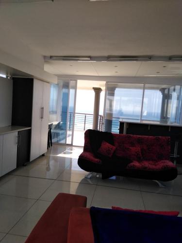 a living room with a red couch in a building at Sancta Maria 10 - Ultimate in luxury & majestic sea views includes private entertainment deck - Free wifi in Kingsburgh