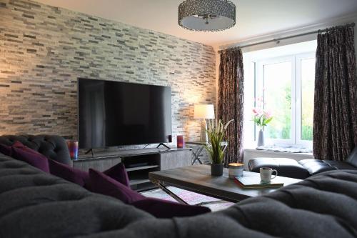 a living room with a tv and a brick wall at Gleneagles Luxury Apartment in Auchterarder