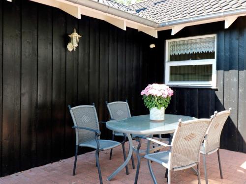 een terrastafel met stoelen en een vaas met bloemen bij 8 person holiday home in Hadsund in Hadsund