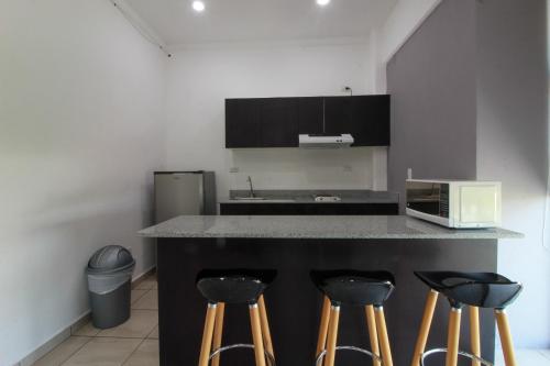 a kitchen with a counter with stools and a microwave at Hotel Boutique Kinyaah in Mérida