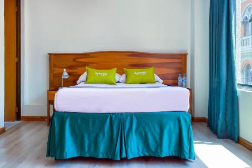 a bedroom with a bed with two green pillows at Ayenda 1140 Roma Plaza in Manizales