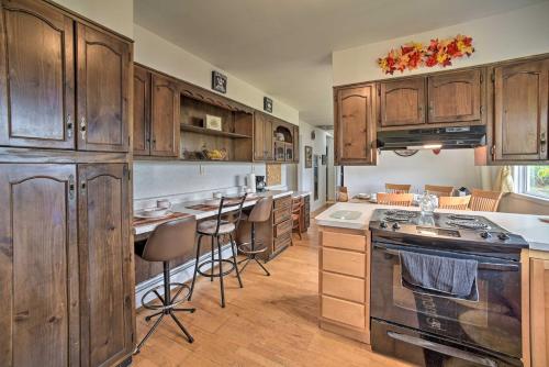 a kitchen with wooden cabinets and an island with bar stools at Albany Home with Fenced Yard and Patio - Pets Welcome! in Albany