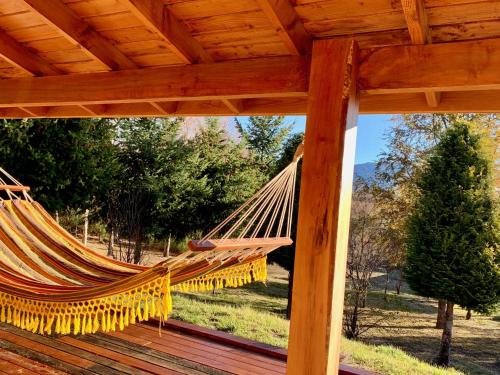 a hammock on a deck with a view of a yard at Fly Fishing Cabin, Great Views in Junín de los Andes