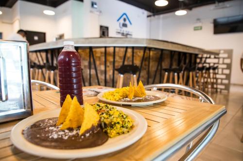 a table with two plates of food and a bottle of drink at Hotel Boutique Kinyaah in Mérida