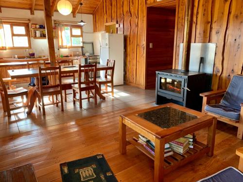 a living room with a table and a stove in a room at Fly Fishing Cabin, Great Views in Junín de los Andes